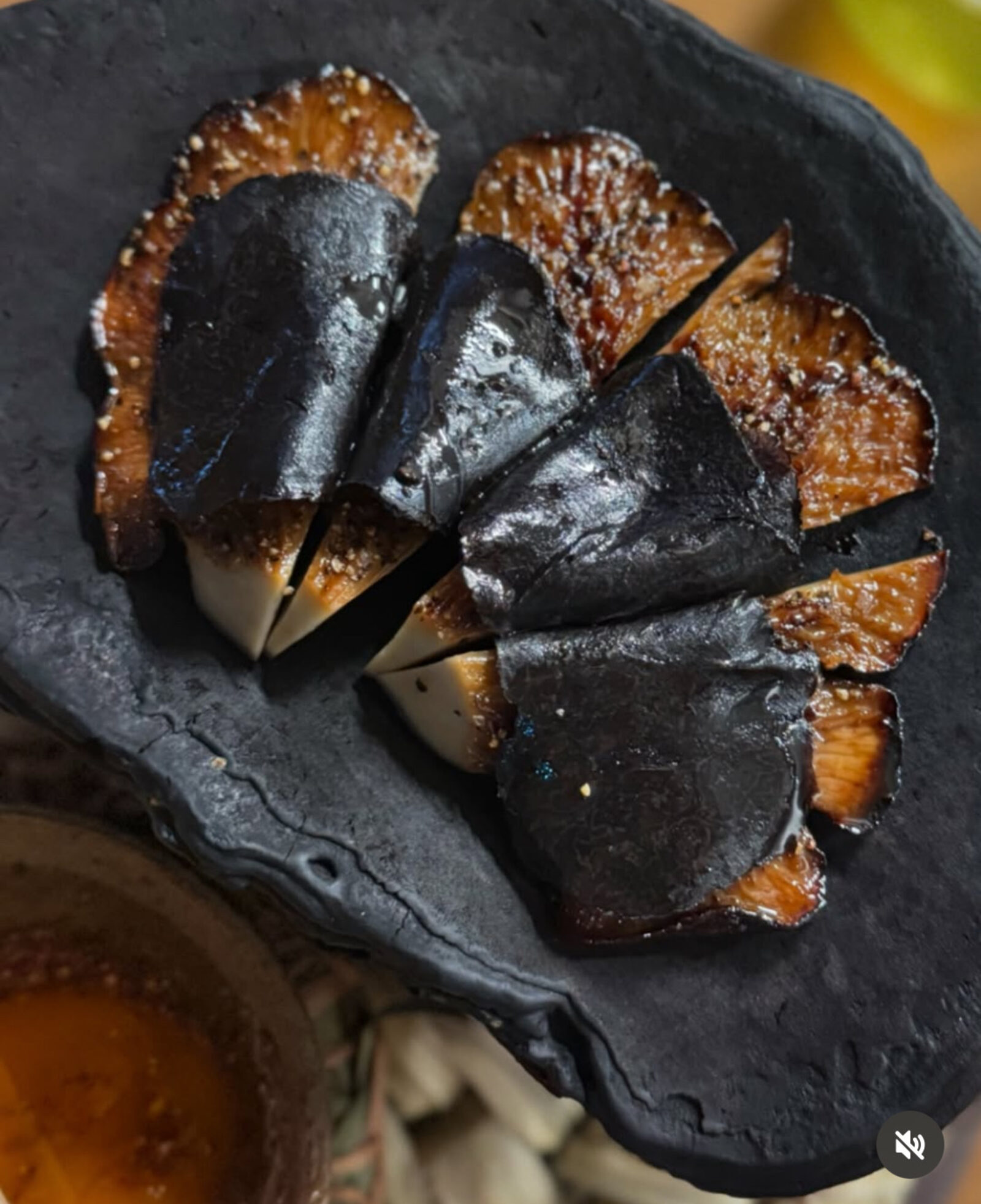 Noma dish — charred mushroom slices on black plate