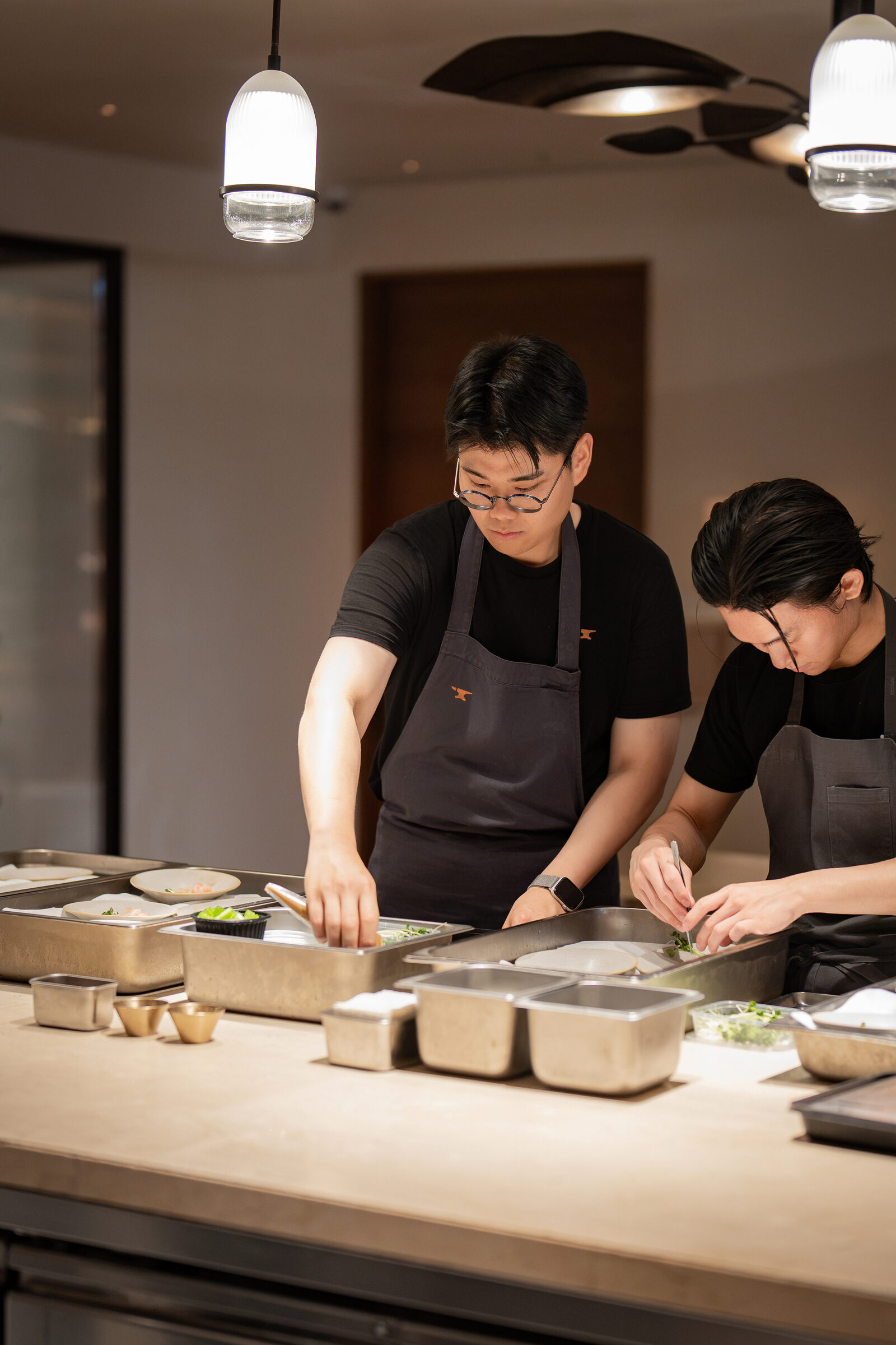 Chefs plating dishes at the pass during the Playa × Jongin Byeon pop-up dinner