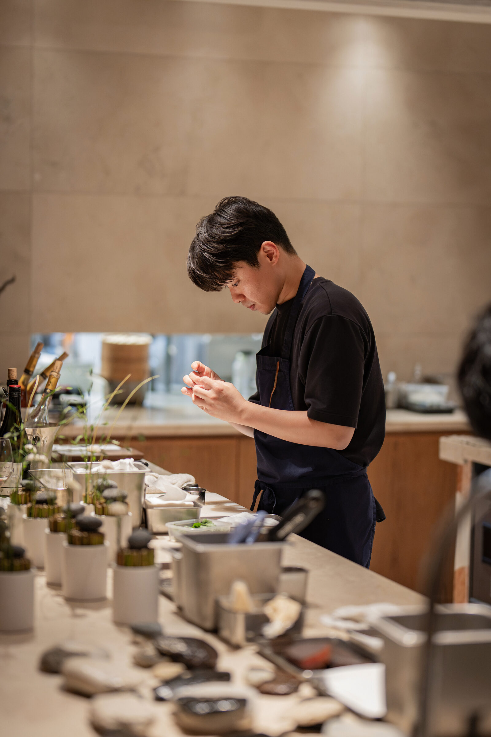 Chef finishing a dish by hand at the counter during the Playa × Jongin Byeon pop-up dinner