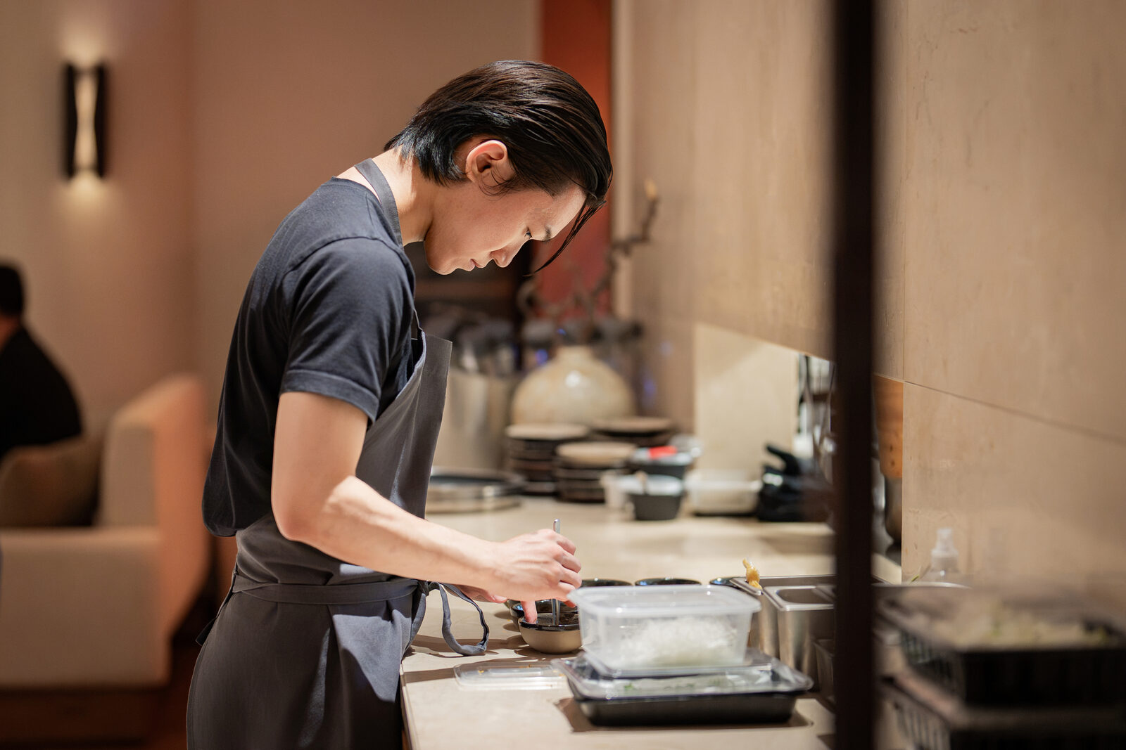 Chef plating a dish at the counter during the Playa × Jongin Byeon pop-up dinner