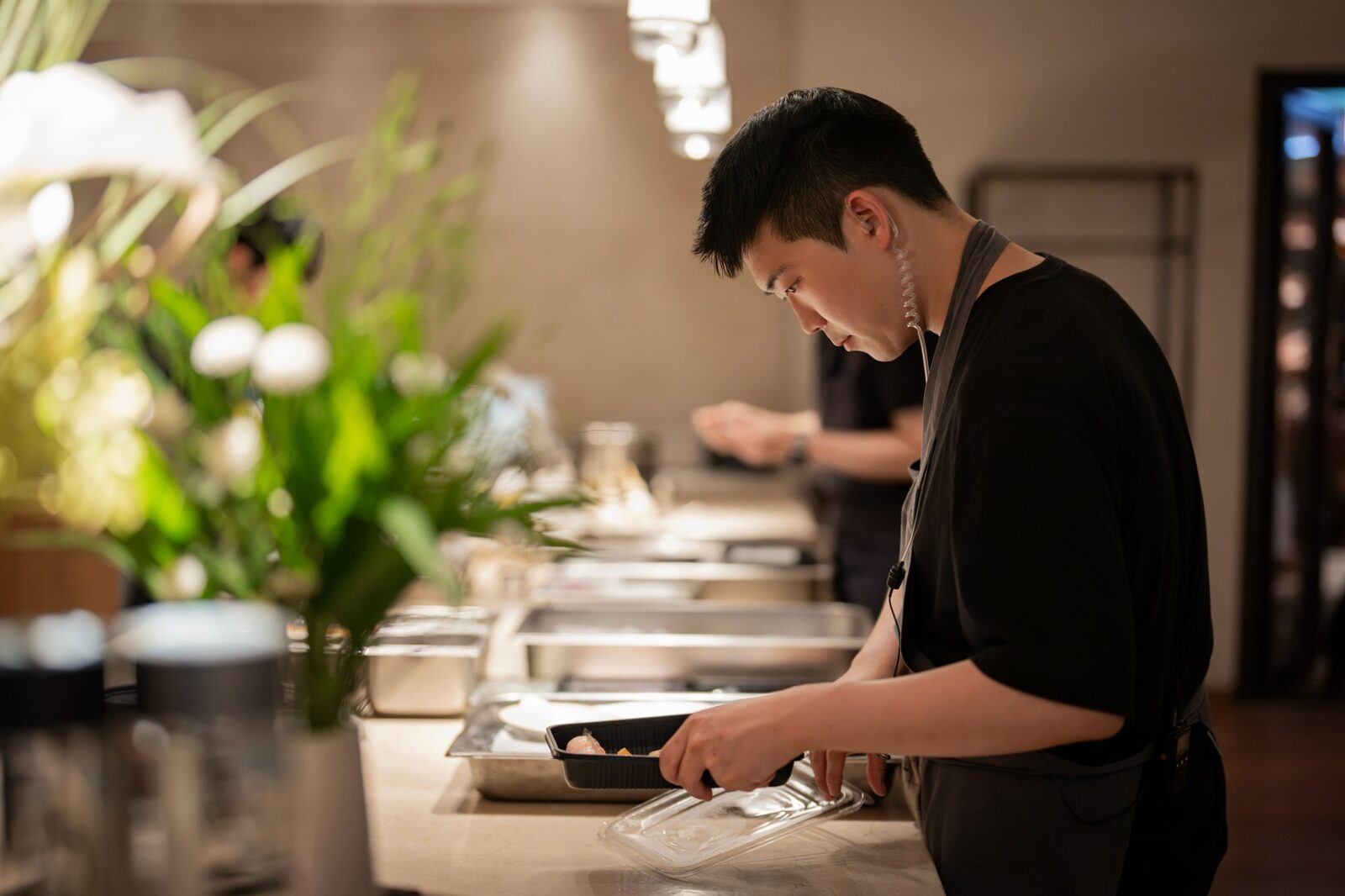 Chef plating a dish at the counter during the Playa × Jongin Byeon pop-up dinner