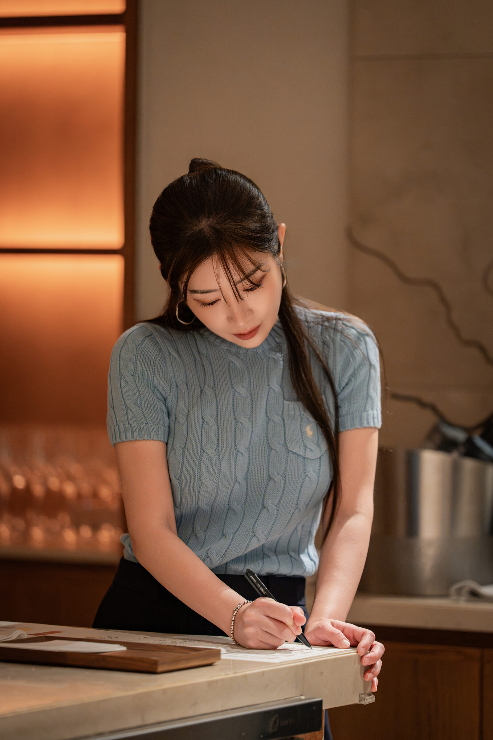 Director writing at the counter during the Playa × Jongin Byeon pop-up dinner