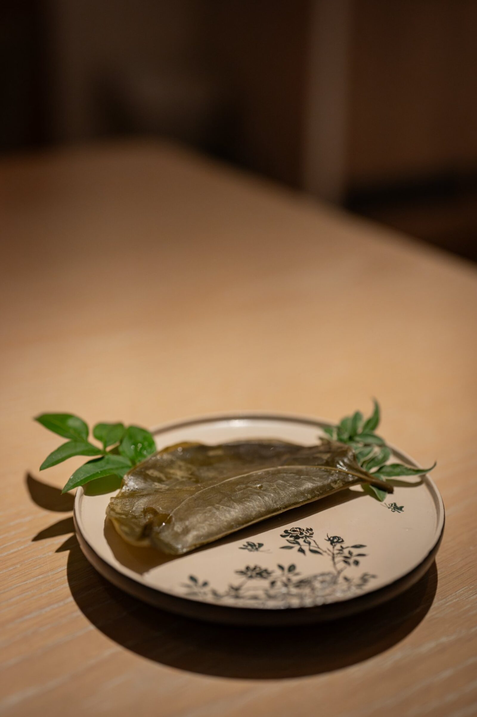 Manggae-tteok wrapped in smilax leaf with pine nut praline plating